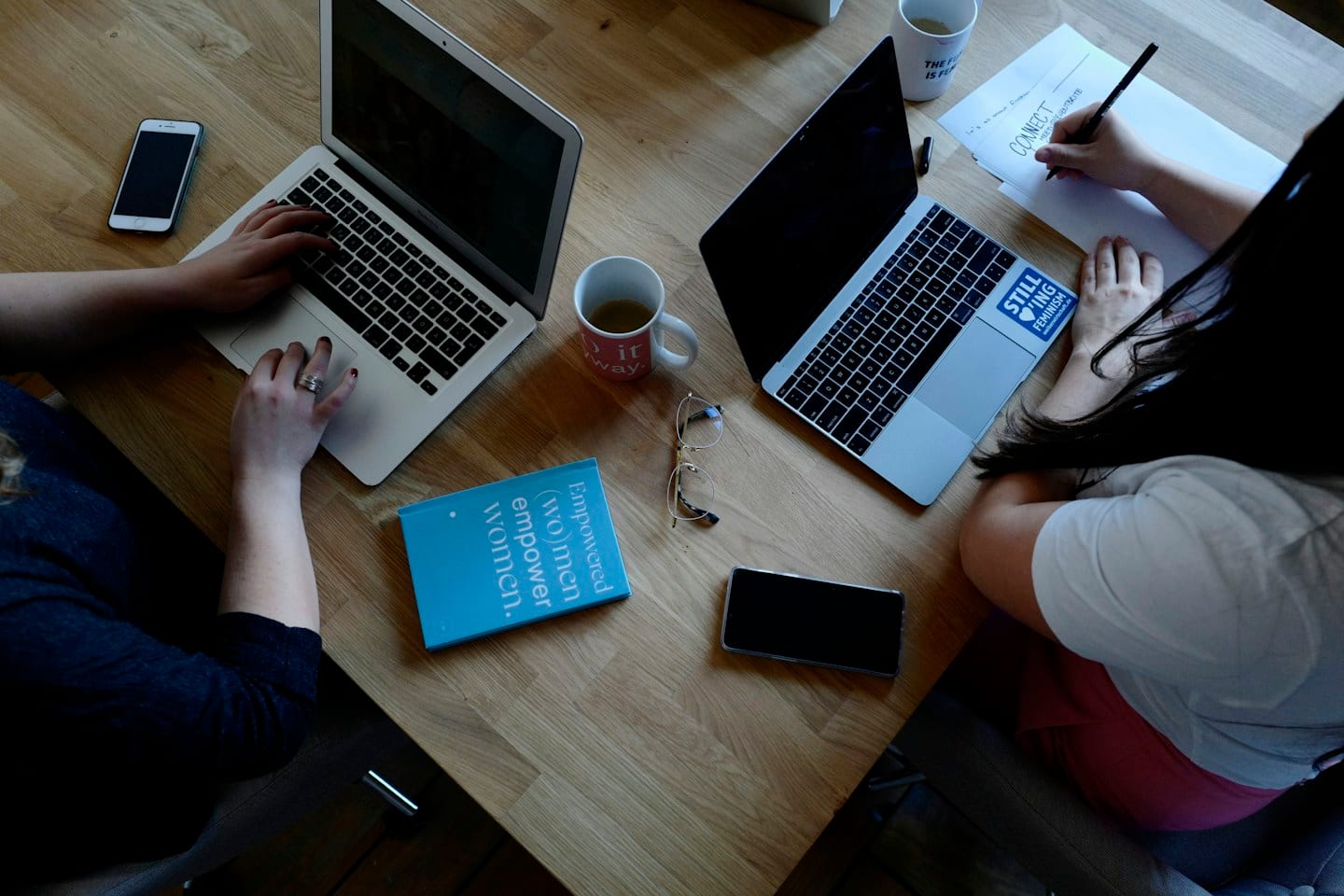 Two people working with laptops; illustrative business photography.